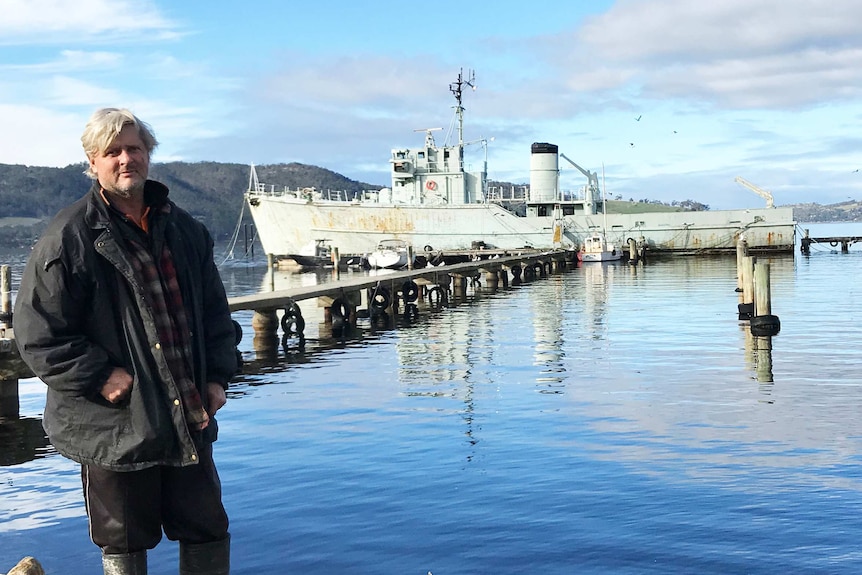 Former Royal Australian Navy minesweeper Curlew, with new owner Kris Mitchell on shore.