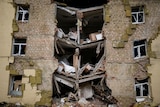 Debris hangs from a partially collapsed multistorey residential building heavily damaged in a Russian bombing.
