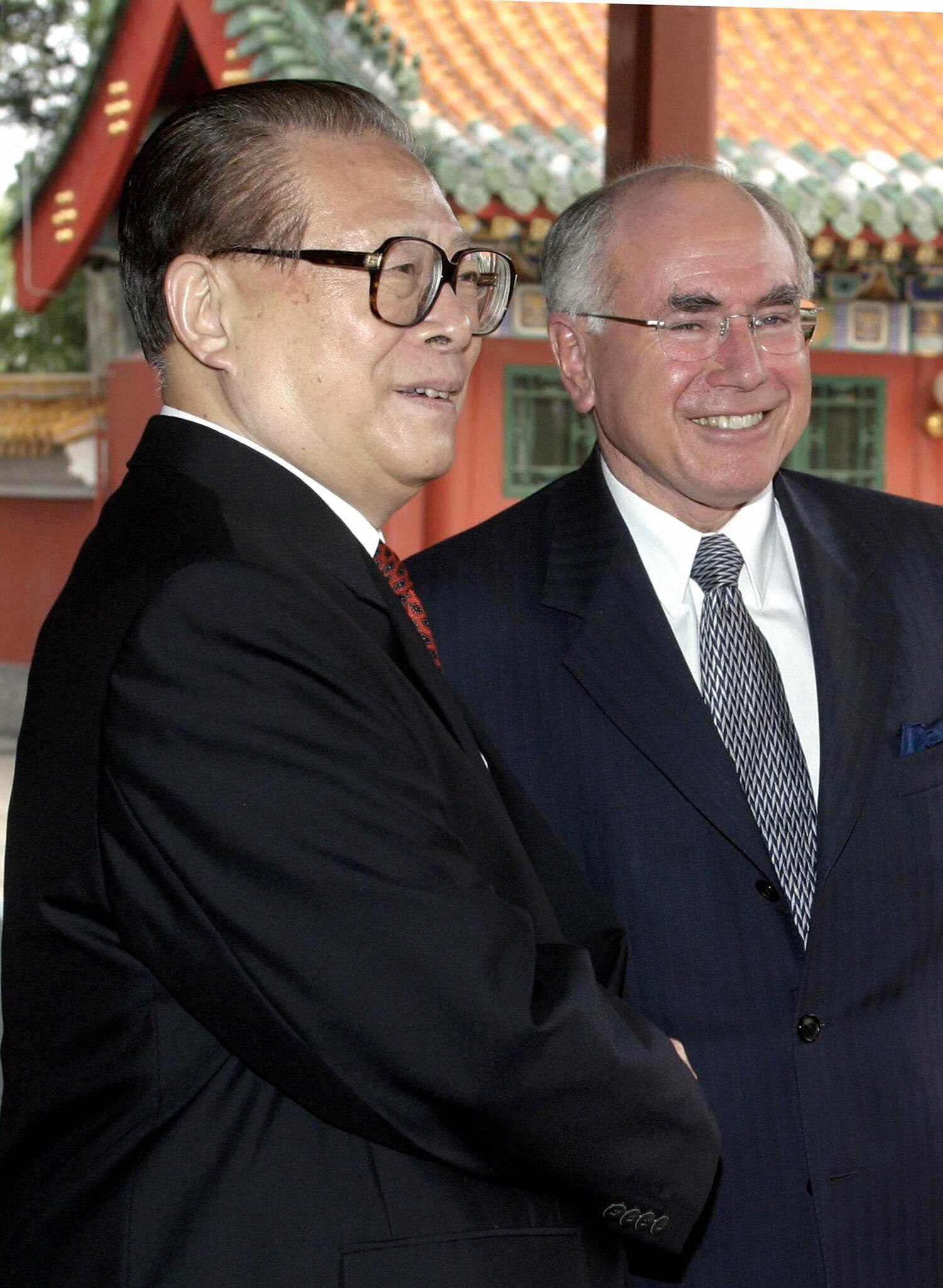 Jiang Zemin and John Howard shake hands and smile.