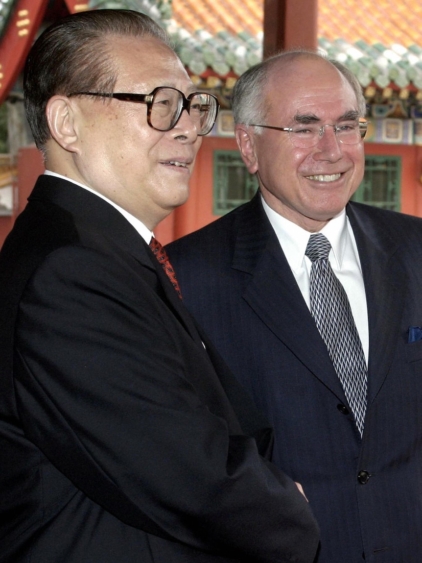 Jiang Zemin and John Howard shake hands and smile.