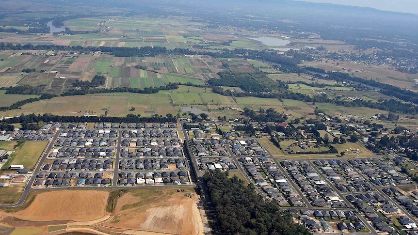 An aerial view of new housing developments on the edge of green farming areas in Sydney.