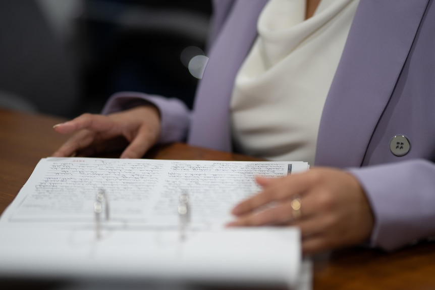 Two hands seen turning the pages of a large folder