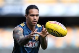 An AFL player holds his hands out to grab the ball at training.