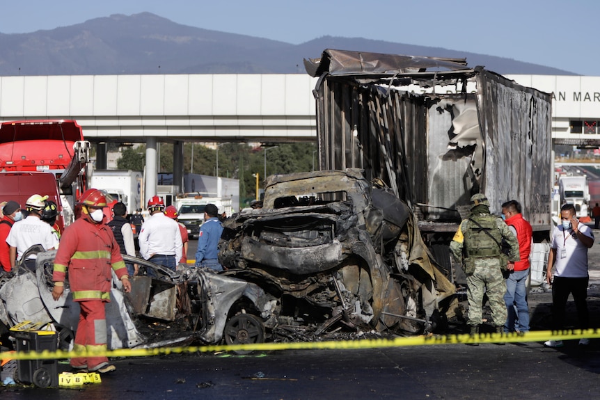 Emergency services personnel work the scene of a deadly accident, inspecting the wreckage of vehicles