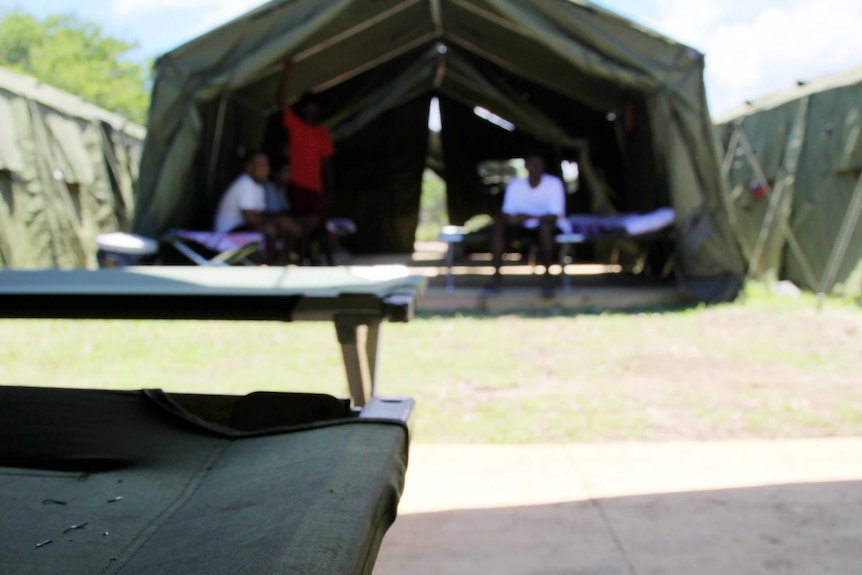 Men sit outside tents