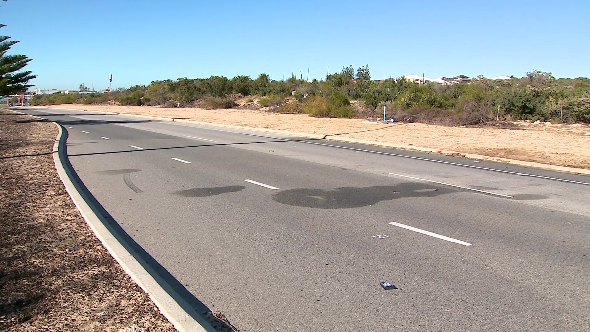 A road runs along the coast that has white markings and a skid mark on it