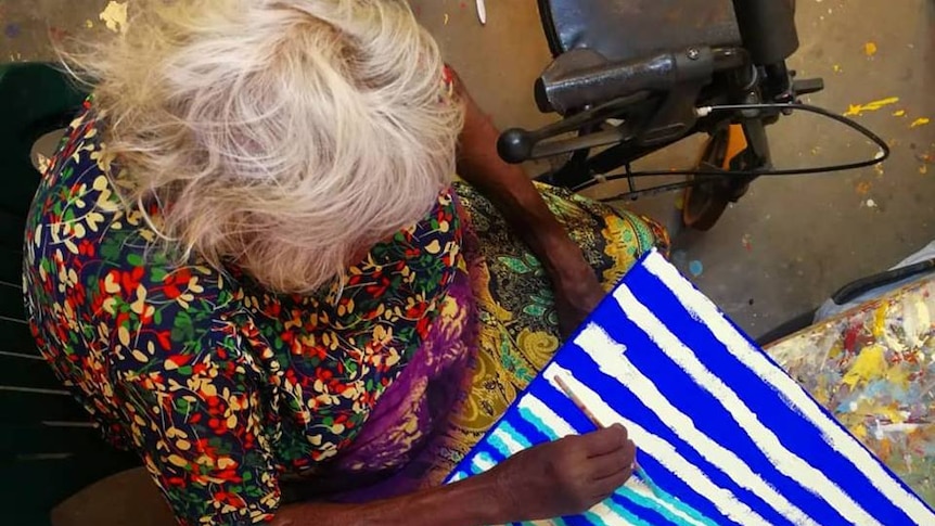 A bird's eye shot of an Aboriginal woman painting