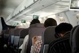A man reads a newspaper on a domestic flight