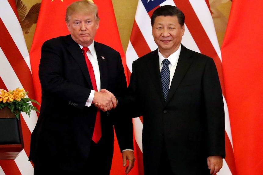 Donald Trump and Xi Jinping shake hands in front of China and US flags.