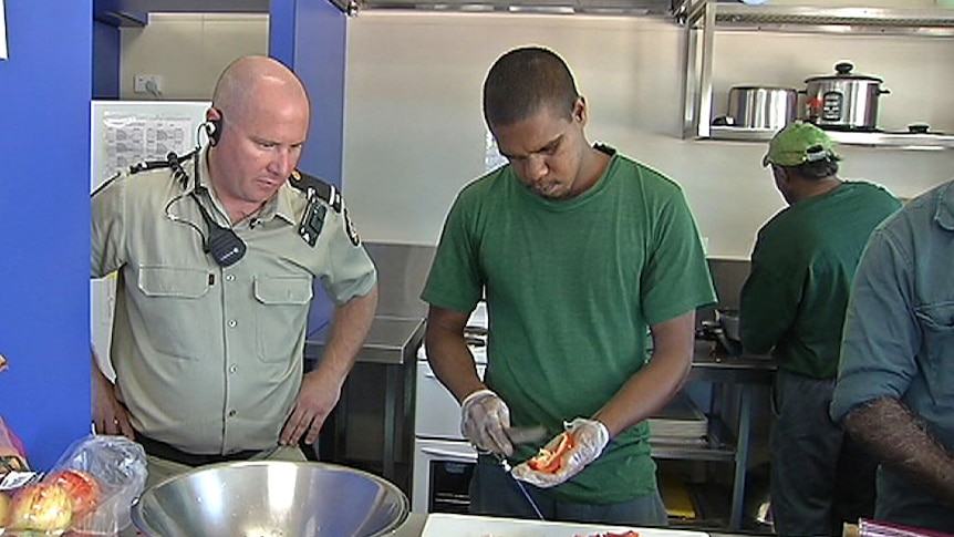 Prisoner Leon Everett participates in a cookery class as a guard watches on.