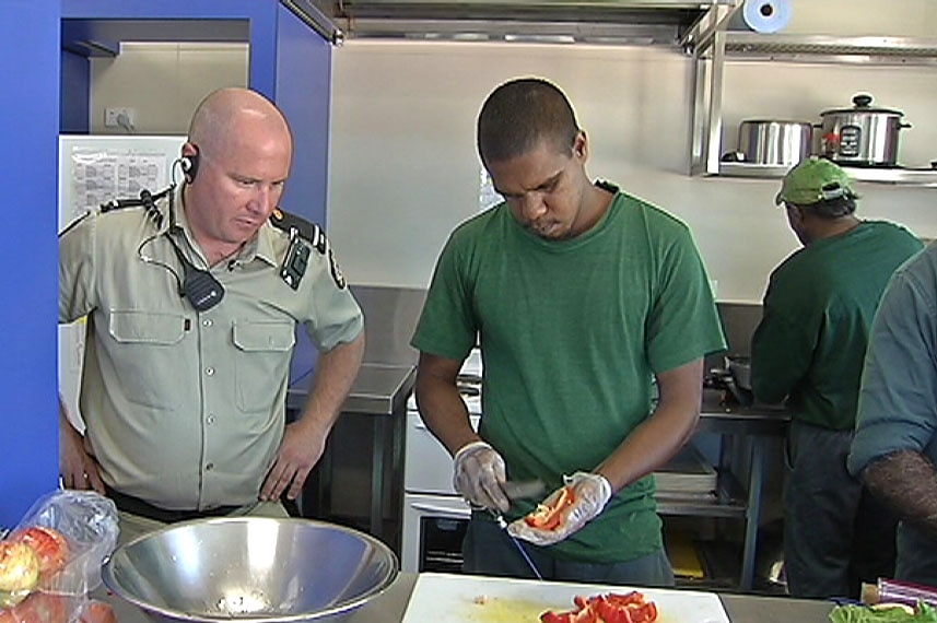 Prisoner Leon Everett participates in a cookery class as a guard watches on.