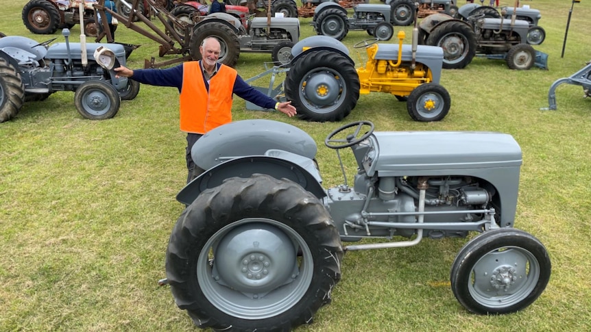 Gerard Gelston stands excitedly in front of a big exhibition of Ferguson tractors.
