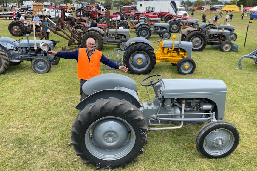 Gerard Gelston stands excitedly in front of a big exhibition of Ferguson tractors.