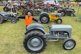 Gerard Gelston stands excitedly in front of a big exhibition of Ferguson tractors.