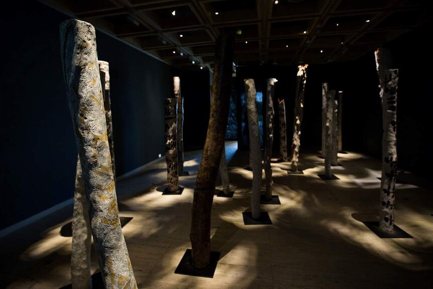 Wooden poles that look like tree stumps inside a darkened room.