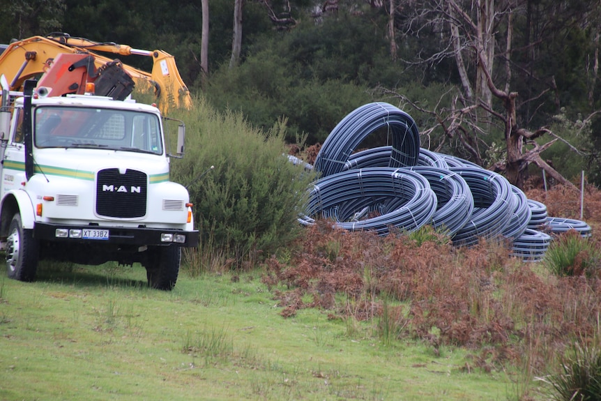 Coiled water pipe and trucks beside a road