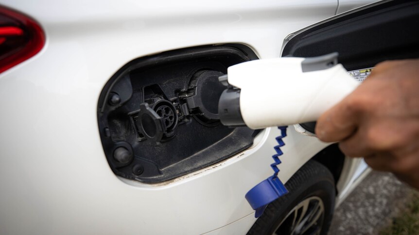 an electric vehicle charger is being plugged into a white car