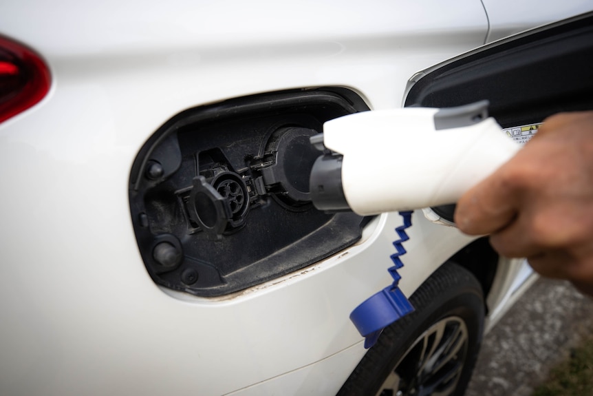an electric vehicle charger is being plugged into a white car