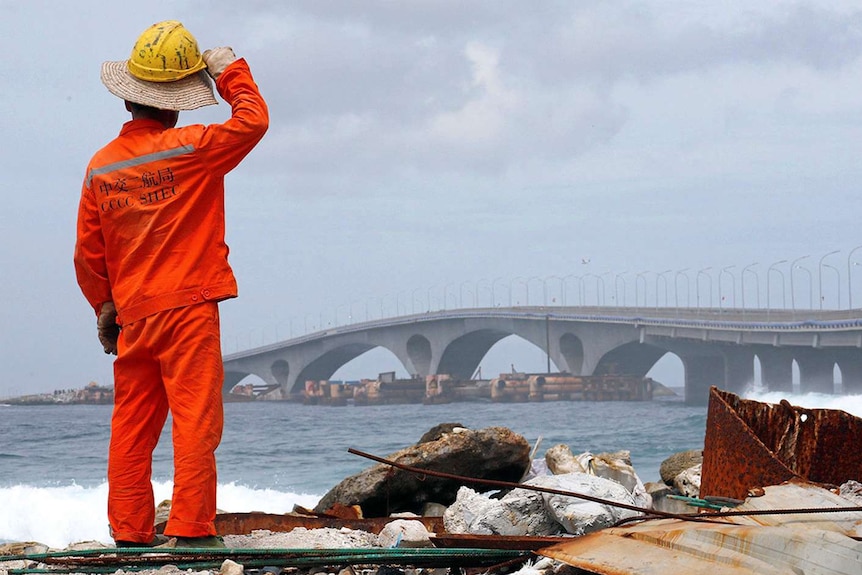 A construction worker looks on as the China-funded Sinamale bridge is seen in Male, Maldives.