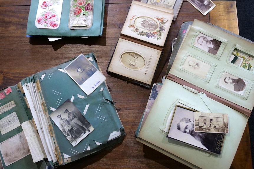 Photo albums open showing historic photos, laid out on coffee table. 