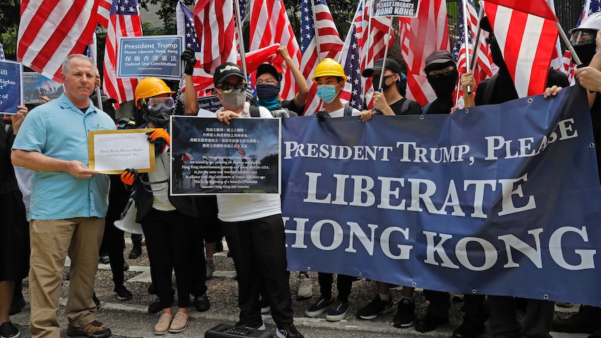 A US Consulate representative, left, receives a letter from protesters who are waving US flags.
