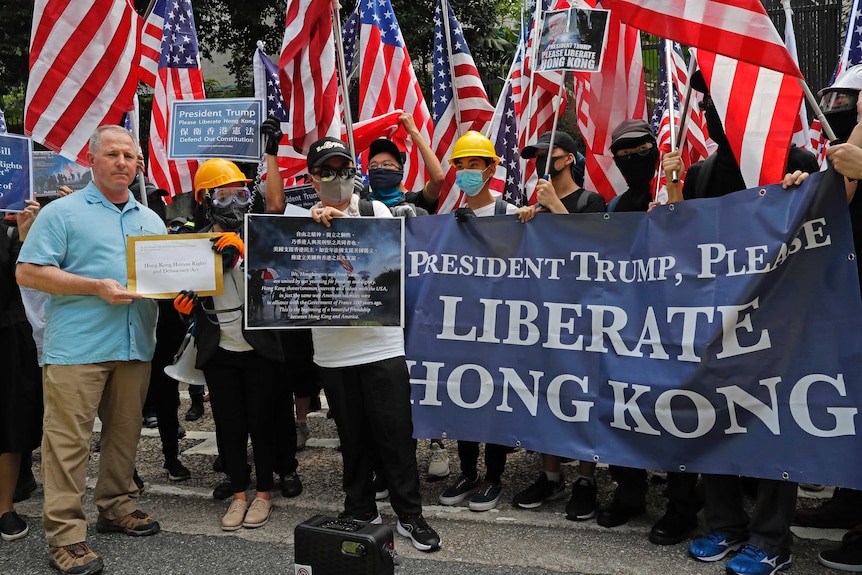 A US Consulate representative, left, receives a letter from protesters who are waving US flags.