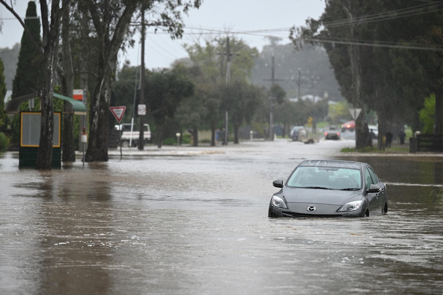 A car rests, partially submerged, in floodwaters in a street in Bendigo.