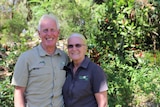 A man with his arms around a women in a green garden