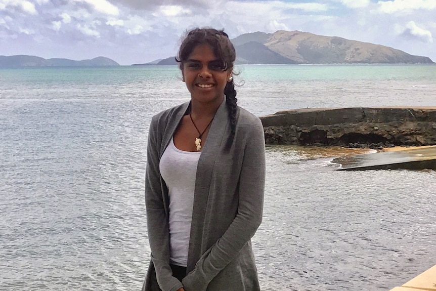 Yvette Nicholas, 19, smiles as she stands on the beach with the ocean in the background on Palm Island.