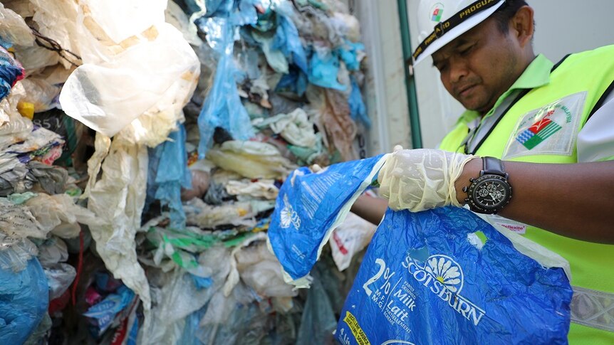 Officials examine plastic waste stacked inside a shipping container