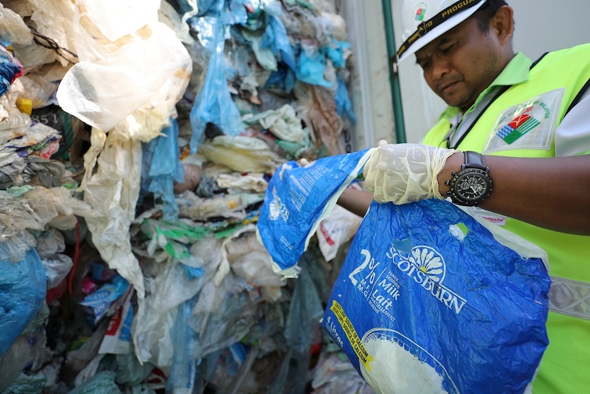 Officials examine plastic waste stacked inside a shipping container