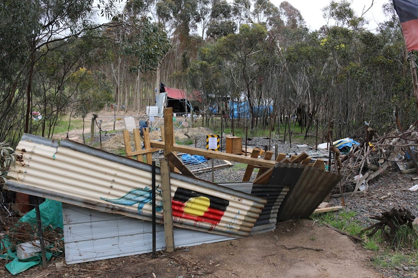 A barricade with makeshift shelters in the background.