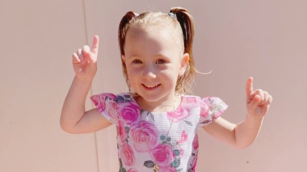 A picture of a little girl smiling in a flower dress