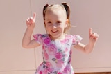 A picture of a little girl smiling in a flower dress