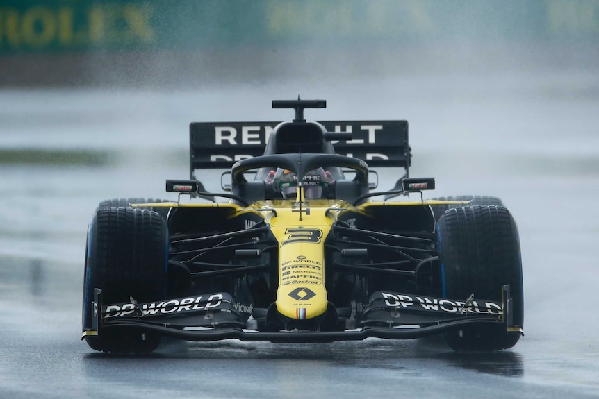 Daniel Ricciardo's yellow car drives through the rain on a wet track