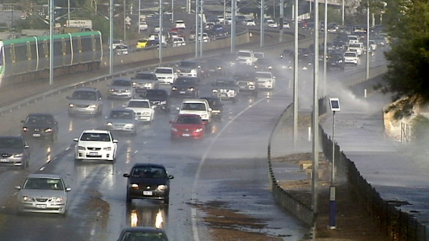 A spray of water covers cars on a freeway.