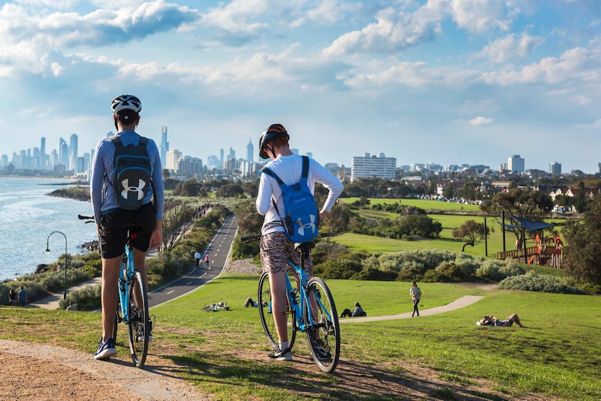 Two people on bikes in a park overlooking the city