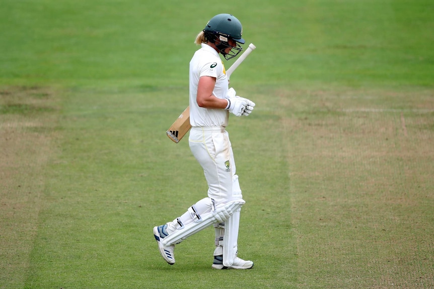 Ellyse Perry walks from the field with her head down and her bat tucked under her arm.