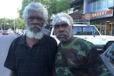 Two Indigenous men stand outside shops in Darwin.