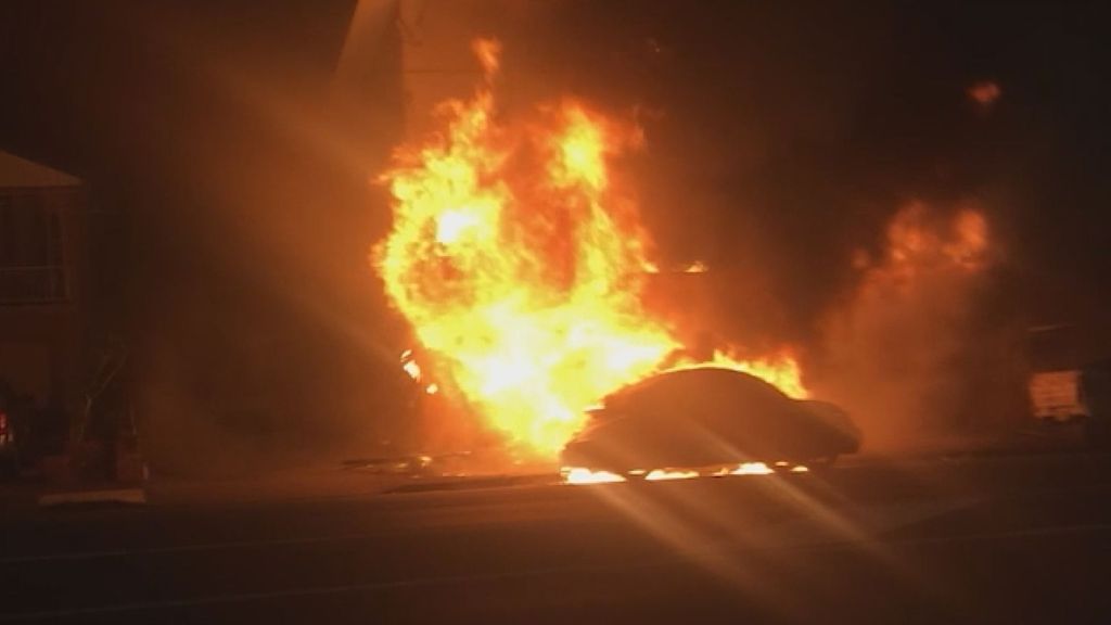 A burning car on a street at night.