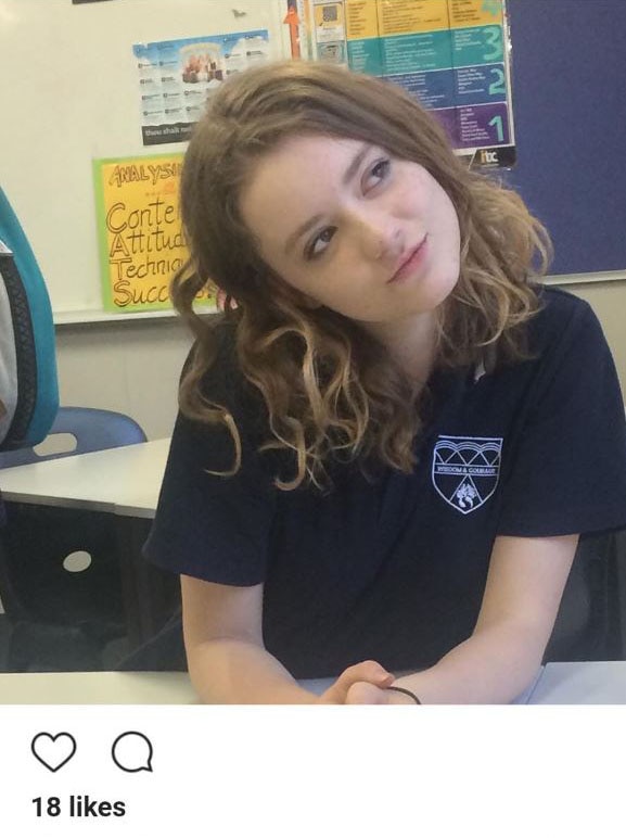Charlotte sits at her desk and tilts her head to one side in a photo posted to instagram taken in her classroom.