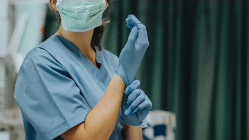 A doctor is putting on medical gloves.