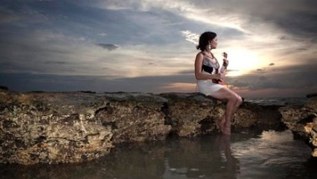 Leah Flanagan sits on the shore line of Darwin by the sunset with her Ukelele.