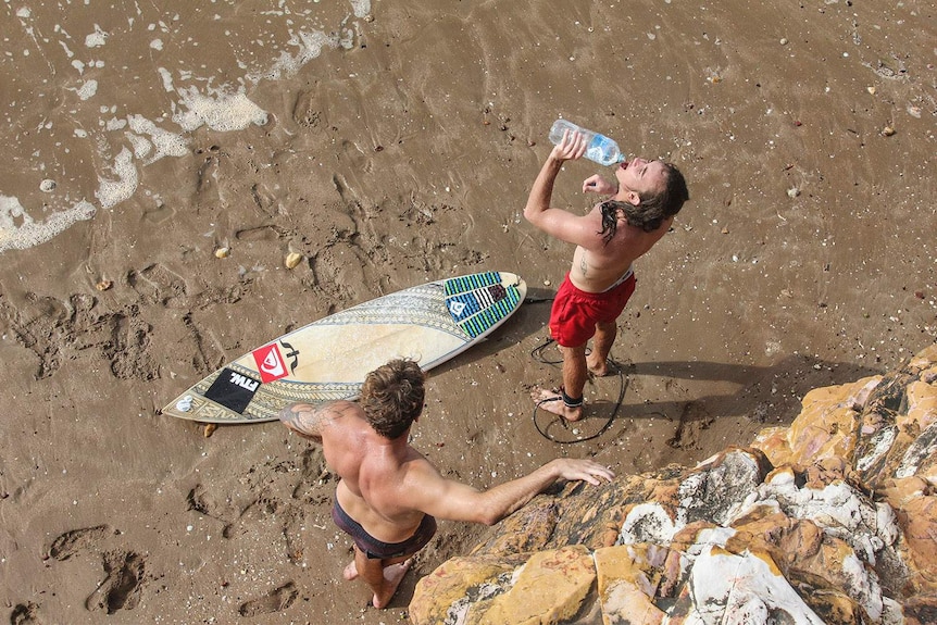 above shot of men drinking water on sand