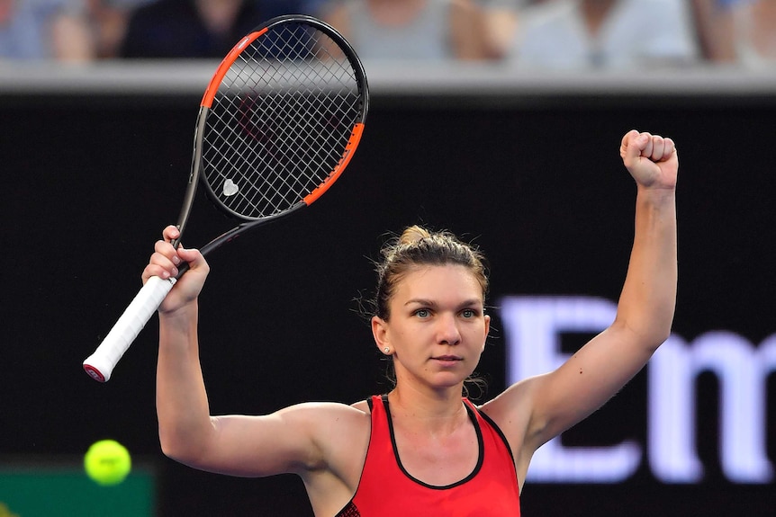 Simona Halep raises both her arms as she celebrates beating Eugenie Bouchard in the Australian Open second round.