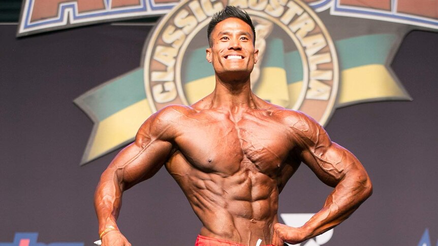 A very muscular Viet Doan with a slender waist poses in a bodybuilding competition.