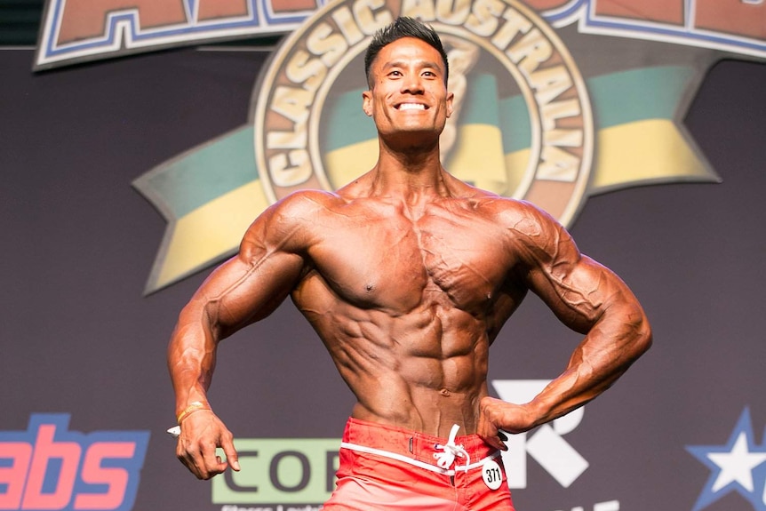 A very muscular Viet Doan with a slender waist poses in a bodybuilding competition.