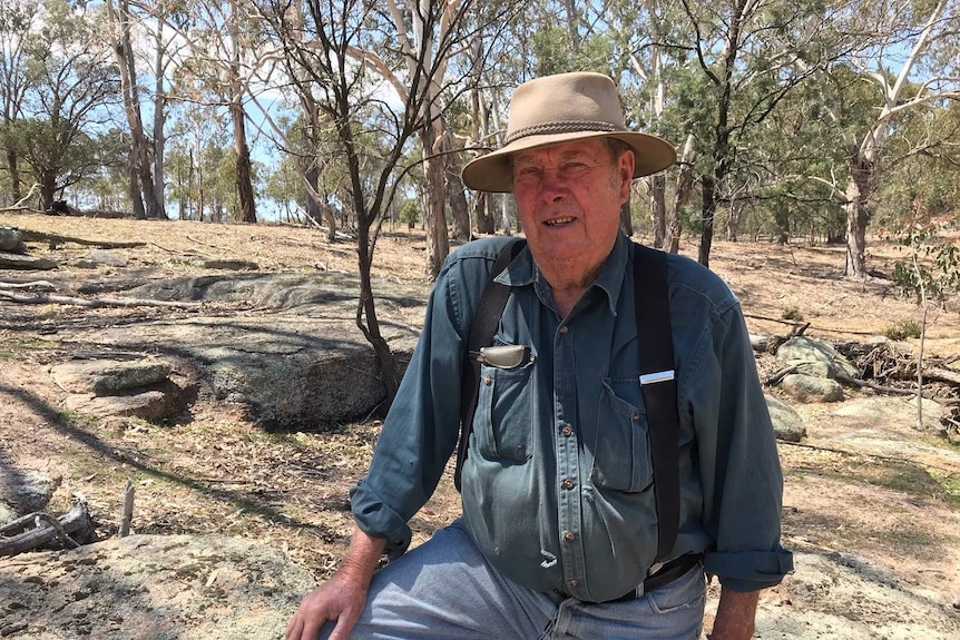 A man in a hat stands in the bush.