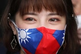 A woman with long hair wears a face mask with the flag of Taiwan on it