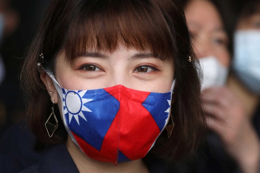 A woman with long hair wears a face mask with the flag of Taiwan on it